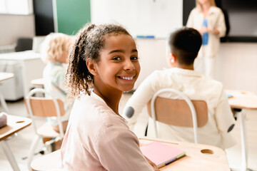 Obraz premium African-american young smart schoolgirl pupil student attending school lesson class listening to the teacher. Back to school. New academic year semester.