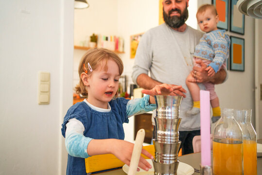 Girl keeping stack of steel glasses on table at home