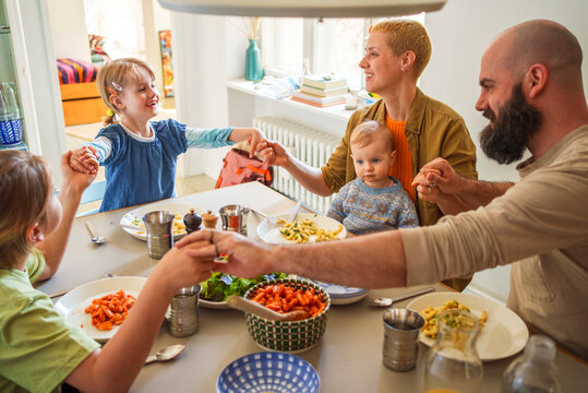 Family praying before lunch sitting at dining table