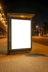 Blank White Mockup Of Bus Stop Vertical Billboard In Front Of Empty City Street Background. Advertising Lightbox On The Sidewalk At Night