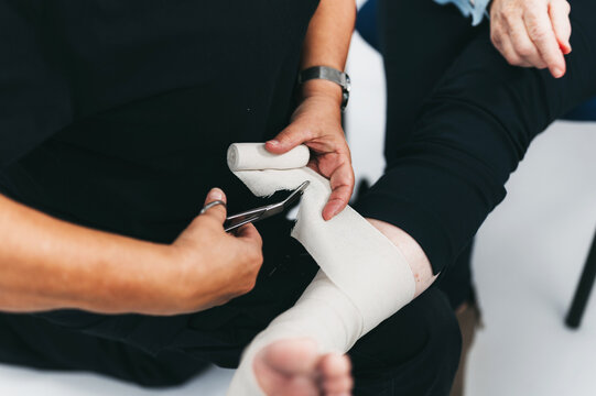Doctor cutting wrapped bandage with scissors