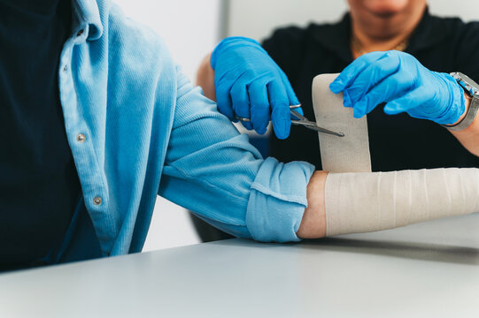 Doctor with gloves cutting wrapped bandage with scissors
