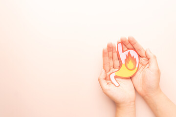 Human stomach burn with acid reflux and fire made from paper on hands. Gastroesophageal reflux disease (GERD) or heartburn symptoms. Gastrointestinal system disease and digestive problems.