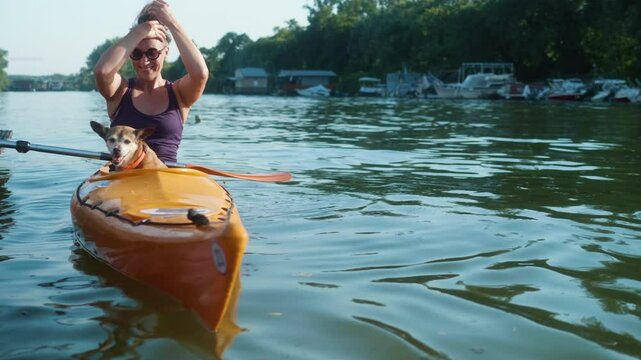 A woman kayaker and her small dog enjoy relaxing on the river