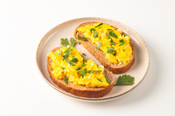 Scrambled eggs with green herbs on wheat-rye crispy toast.