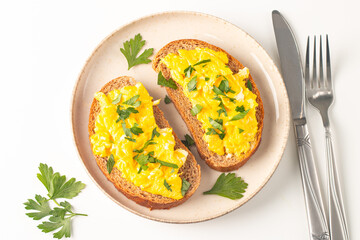 Scrambled eggs with green herbs on wheat-rye crispy toast.