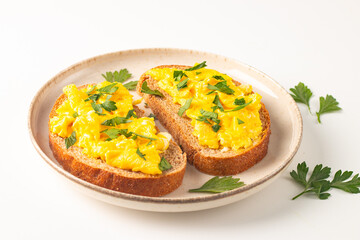 Scrambled eggs with green herbs on wheat-rye crispy toast.