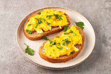 Scrambled eggs with green herbs on wheat-rye crispy toast.