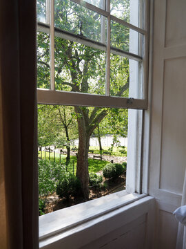 An open sash window looking out onto a lovely park in the summer