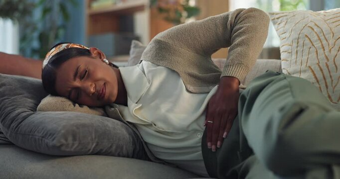 Home, sofa and woman with stomach in pain for indigestion, menstruation and constipation in virus. Living room, person and abdomen with tummy ache for ibs cramps, diarrhea problem and gastro issue