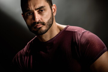Portrait of strong handsome man with brutal unshaven face posing on dark background, Dark allure:...