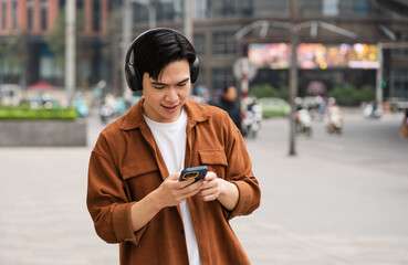 Obraz premium Handsome long legs of Asian men walking, listening to music and working on the street