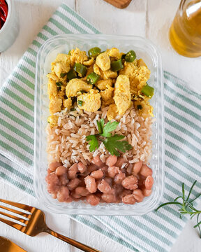 marmita de comida saud&aacute;vel embalagem pl&aacute;stica sobre pano de prato ou guardanapo de tecido, com frango em peda&ccedil;os, arroz integral, feij&atilde;o carioca