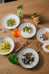 Overview of fancy restaurant food plates with drinks on a wooden table