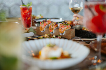 Closeup of taco's on a filled fancy restaurant table with cocktail and wine