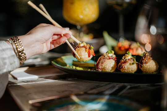 Closeup shot of asian food on a plate with a person using chopsticks