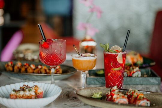 Close-up shot of three cocktails on a restaurant table filled with delicious food