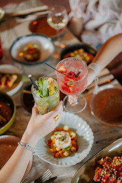 Close-up shot of two cocktails above a filled restaurant table full of food