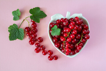 Fresh ripe red currant berries on a berry-shaped bowl on a pink background