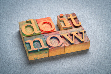 do it now - motivational text in retro letterpress wood type stained by color inks, productivity concept