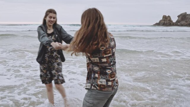 Joyful Gen Z couple enjoys fun summer evening at the beach, running, walking on sand in the ocean. Embracing love, happiness, smile, savor vacation together on the coast, creating lasting memories.