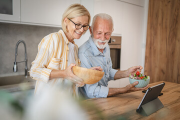 Senior couple have breakfast together and use digital tablet