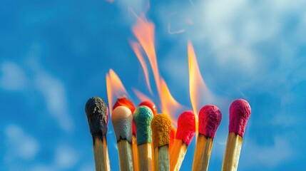 Group of colorful safety matches burning against a blue sky background