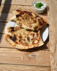 Flat bread on white plate on wooden background