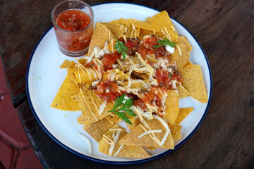 Nachos is a Mexican culinary dish consisting of tortilla chips covered in cheese or cheese sauce