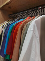 Obraz premium Colorful and stylish clothes on a rack in a wooden wardrobe