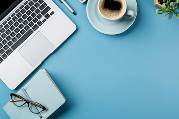 Top view of office desk with laptop, coffee cup and notebook on blue background for work online concept. Flat lay, top view, copy space, stock photo. In the style of stock photo.