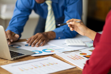 Meeting of business people discussing financial data analysis and business charts. Coworkers working on paperwork on the desk.