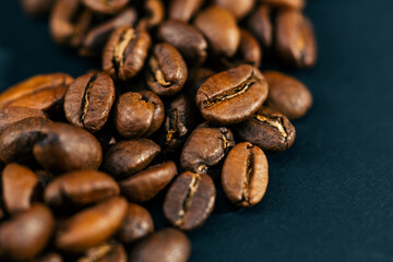 Obraz premium close-up on black-blue background lie roasted coffee beans laid out in the shape of a heart 