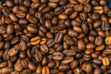 close-up on black-blue background lie roasted coffee beans laid out in the shape of a heart 