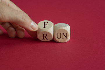 Hand is turning a cube and changes the word Fun to Run. Beautiful red background. Lifestyle concept.