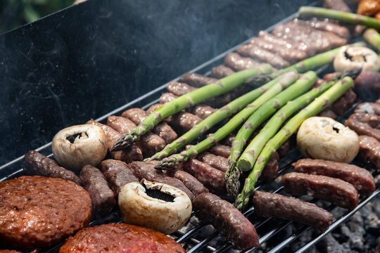 Meat and green asparagus grilling on a metal grate