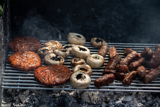 Cooked patties and mushrooms on an outdoor grill