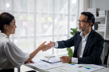 A man shakes a woman's hand in a business setting