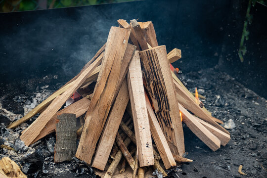 Split kindling stacked on a barbecue grate before lighting