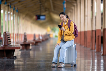 A woman sitting on a suitcase in a train station