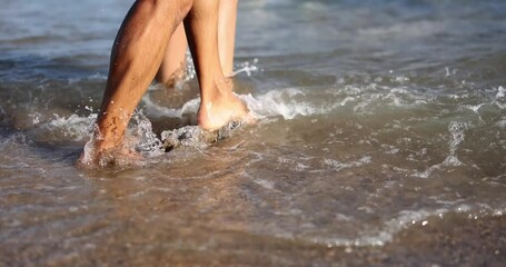 People kick rolling sea waves with bare feet at resort slow motion. Active tourists enjoy day on beach. Couple plays with ocean water on holiday