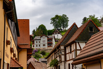 A row of houses with brown roofs and white trim. The houses are on a hill and have a lot of trees around them