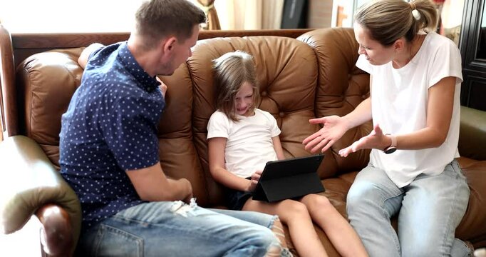 Angry parents scold junior schoolgirl addicted from tablet computer on sofa at home slow motion. Naughty child depended from video games. Parenthood problems