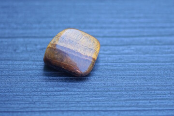 one small brown stone lies on a black wooden table