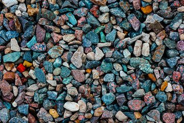 Background with the texture of colored rough pebbles. Dark wet pebbles. Photo from above
