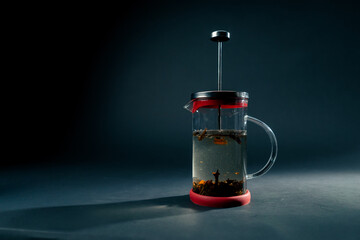 Obraz premium on a dark blue background with side lighting there is glass modern teapot with a press brewing green tea