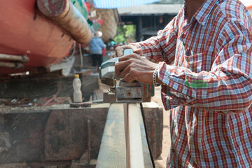 Carpenter is sanding wood with an electric planer.