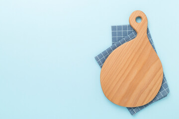 Cutting board with napkin on color background, top view