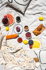Picnic blanket spread in park with fruits, drinks and croissants