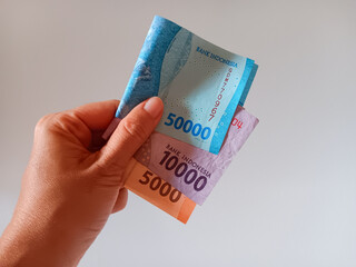 Asian woman's hand holding cash money Indonesian currency rupiah isolated on white background.
